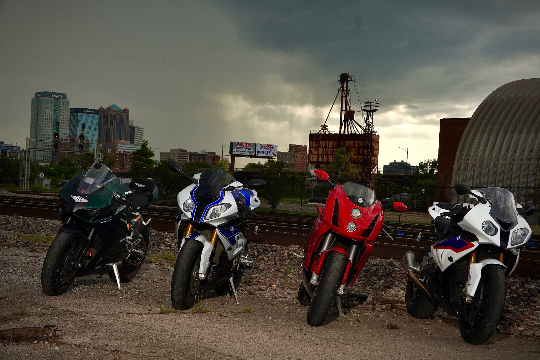 Lineup of sportbikes photographed in front of the Birmingham skyline.