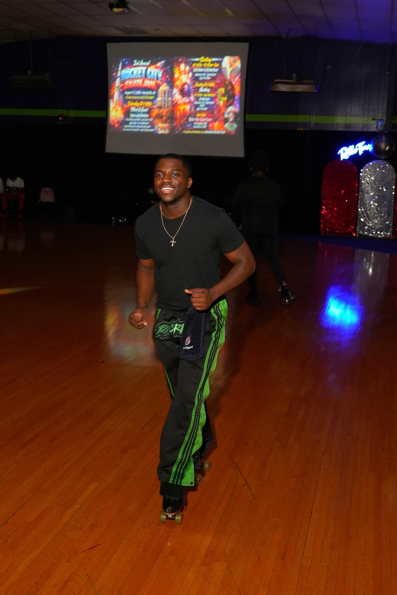 Roller skater in neon green-striped pants gliding across the rink at a themed skate night.