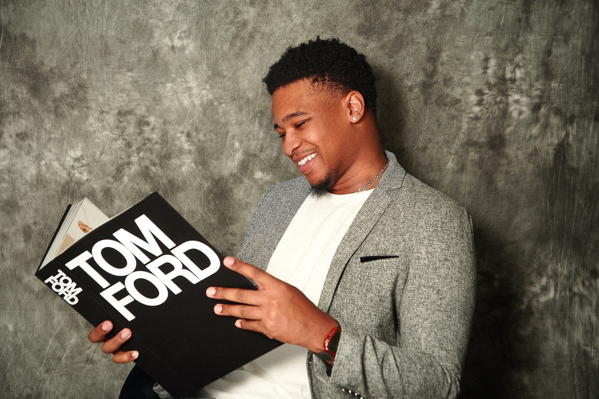 Portrait of a man in a gray blazer reading a Tom Ford book.
