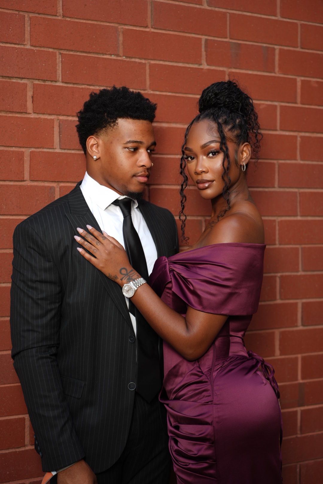 Formal couple portrait against a red brick wall.