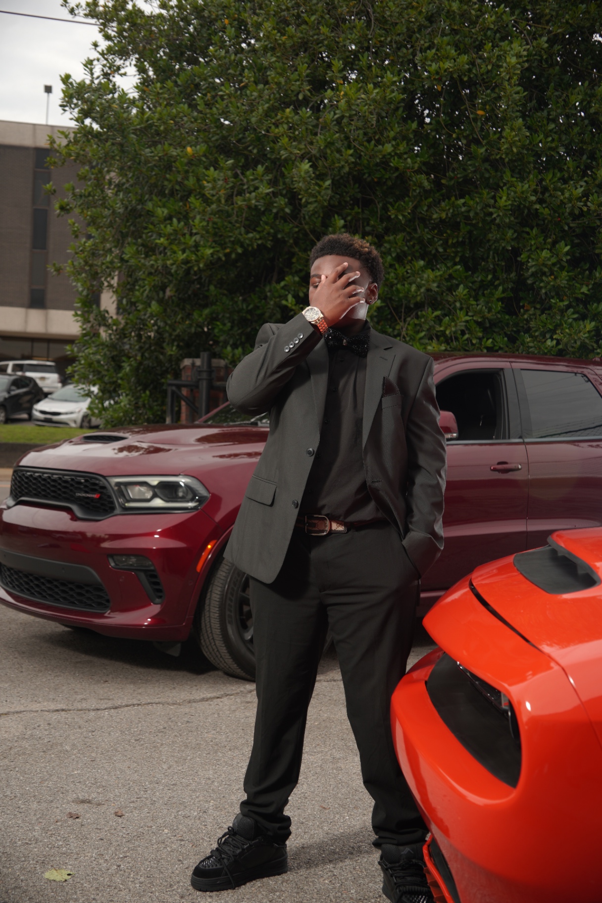 Formal portrait photographed between two cars.