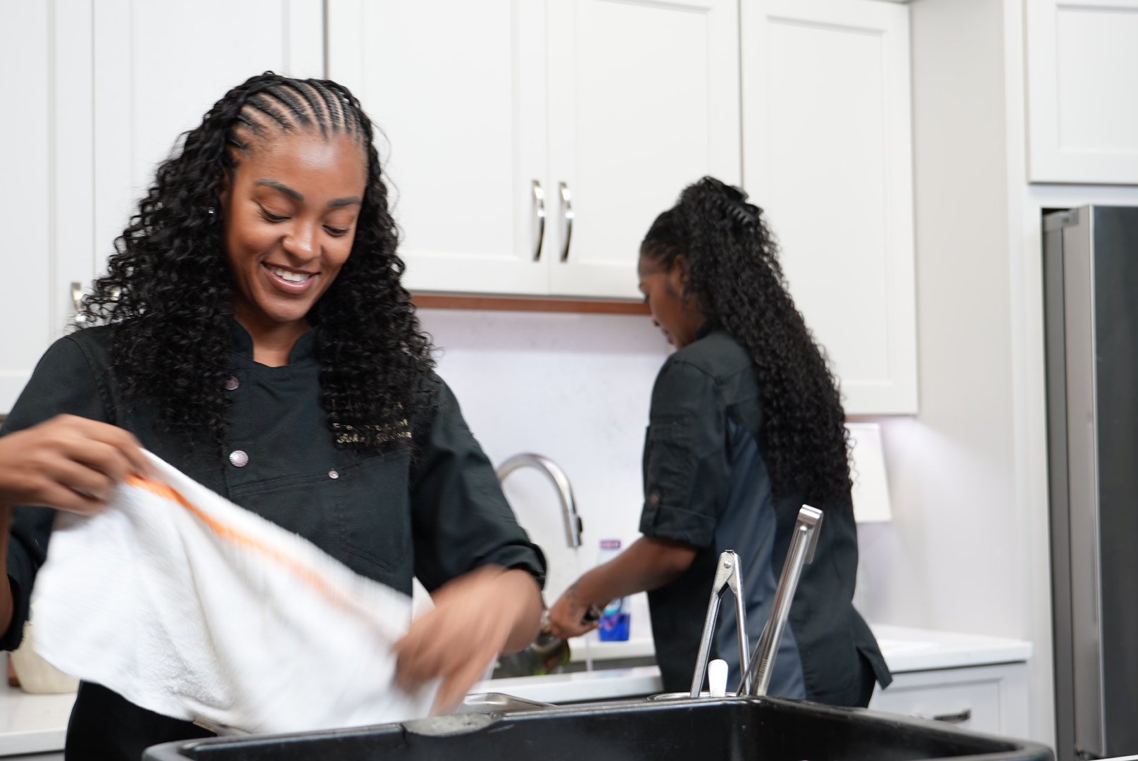 Two chefs working together in a bright white kitchen.