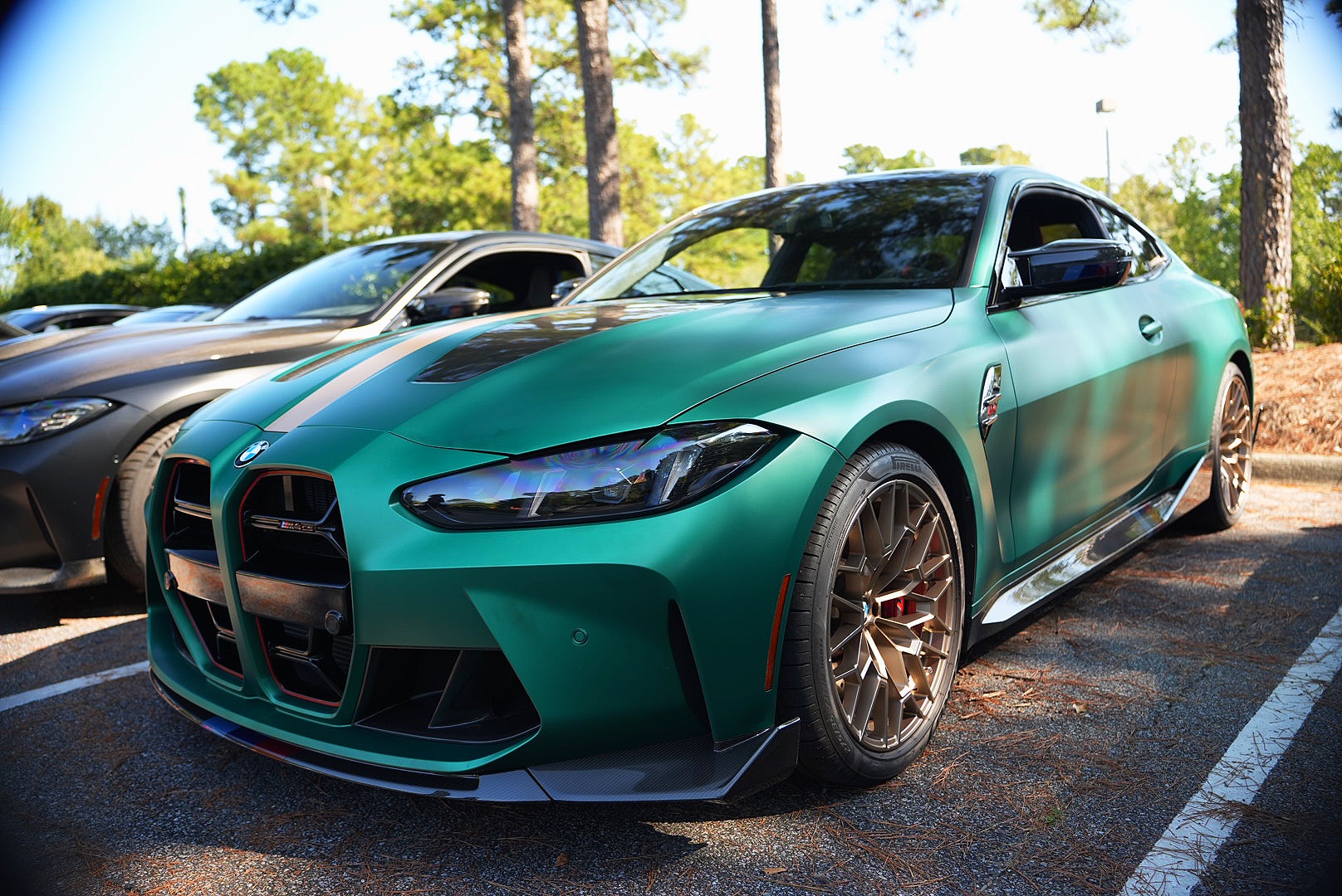 Green BMW M4 CS with bronze wheels photographed at a car meet.
