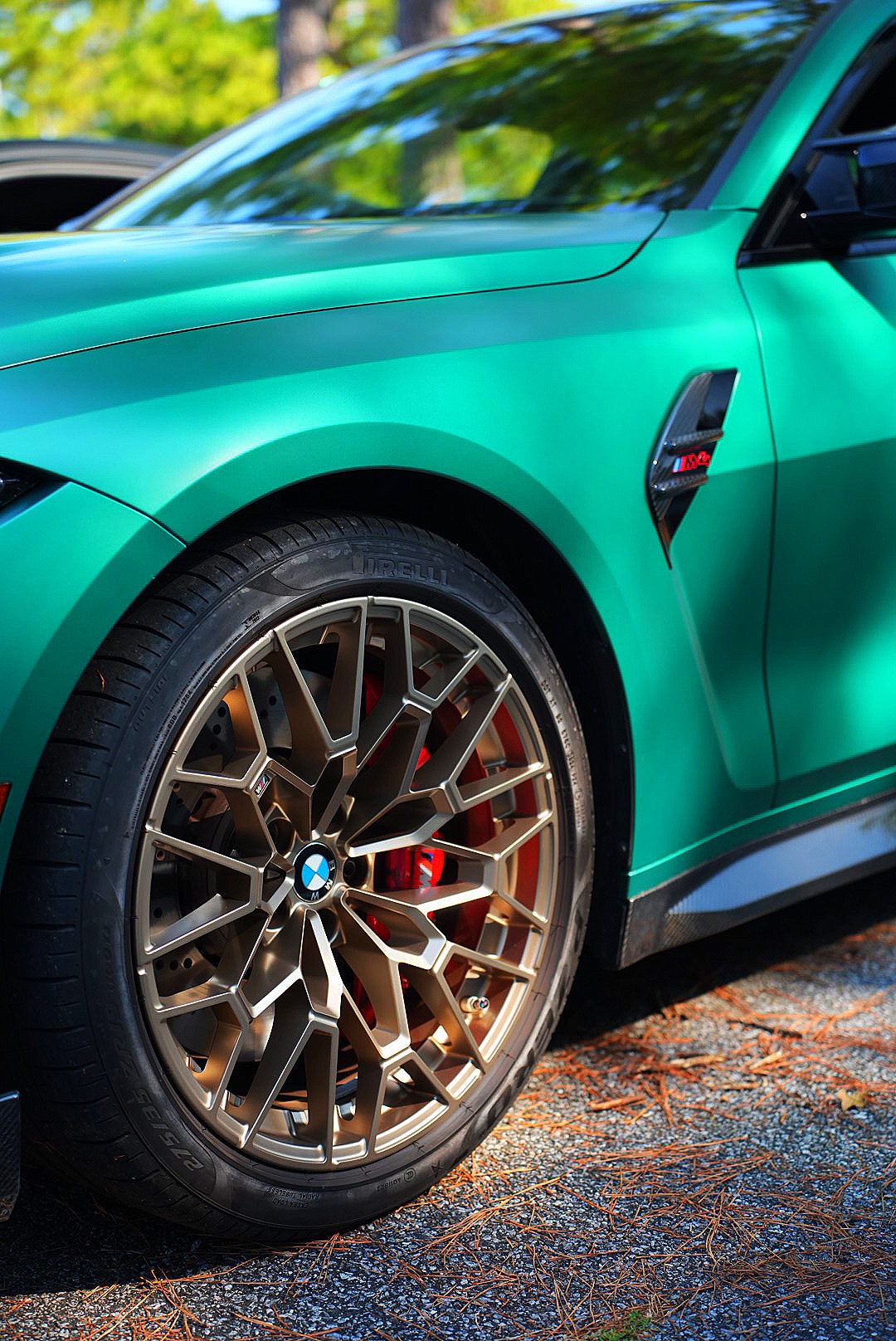 Bronze wheel and fender detail of a green BMW M4 CS.