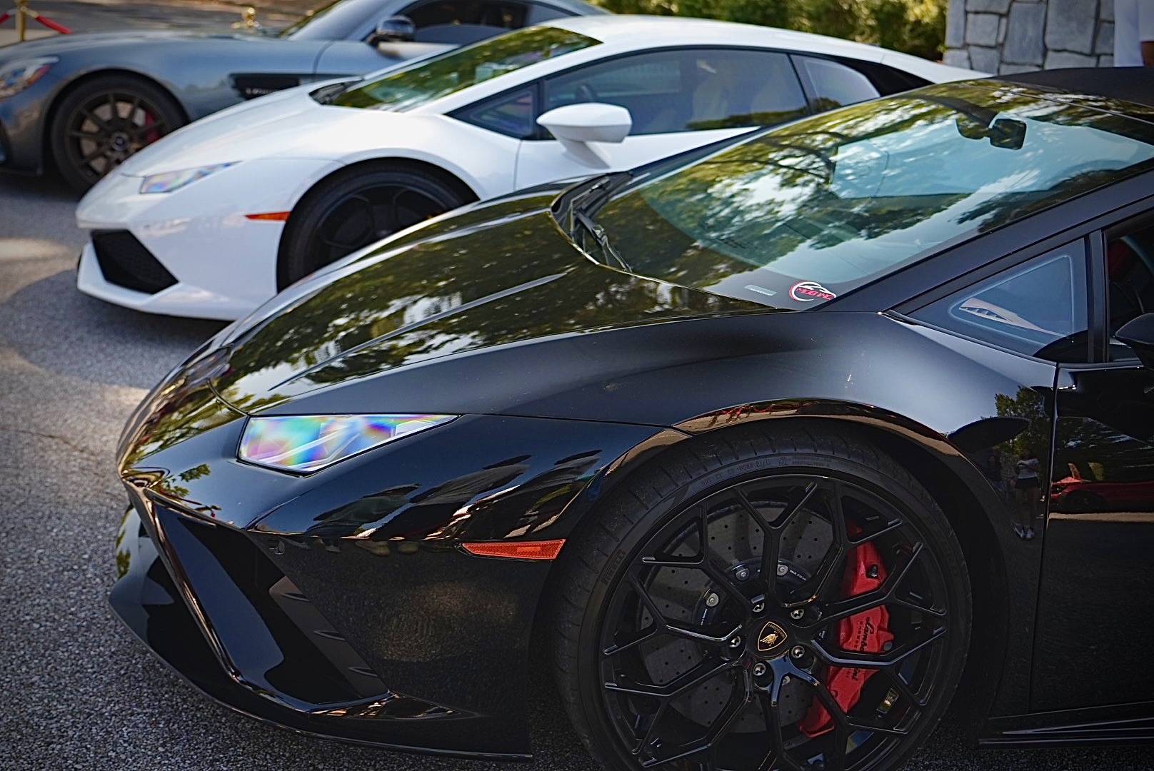 Black Lamborghini Huracán in front of a white Lamborghini at a car meet.